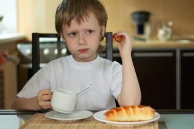 The little boy has decided to have breakfast clipart