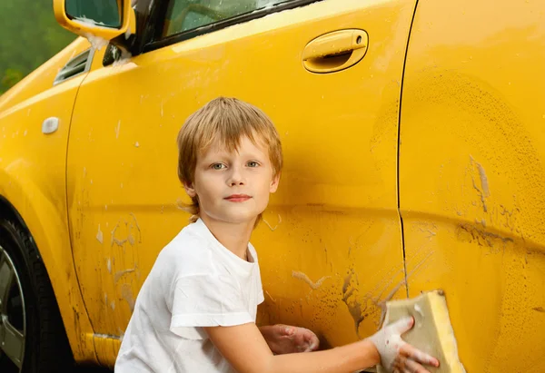 Little boy washing yellow car. — Stockfoto