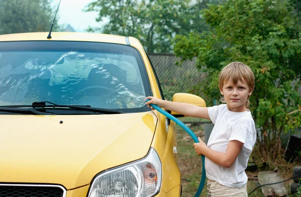 Маленький мальчик моет желтую машину . — стоковое фото