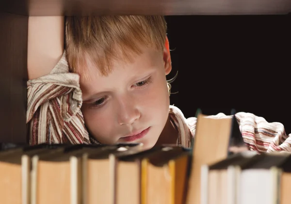 Der Junge am Bücherregal bekommt das Buch. — Stockfoto