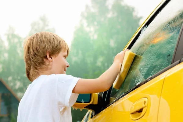Little boy washing yellow car. — Stockfoto