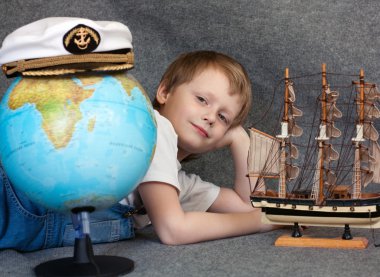 Portrait of the dreaming child with the model ship and globe clipart