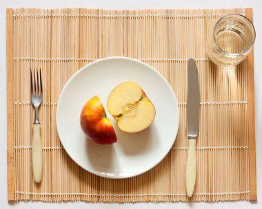 Apple bir plaka üzerinde. bıçak, çatal ve su bardağı.