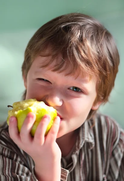 这个七岁的孩子眨了眨眼 吃了一个苹果 — 图库照片
