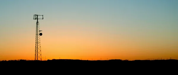 Blek blå mobiltelefon tower sunset — Stockfoto
