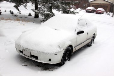 tamamen karla kaplı bir driveway içinde oturan bir araba.