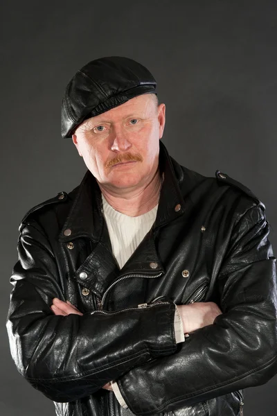 Middle-aged male dressed in leather posing as biker in studio — Stock Photo, Image