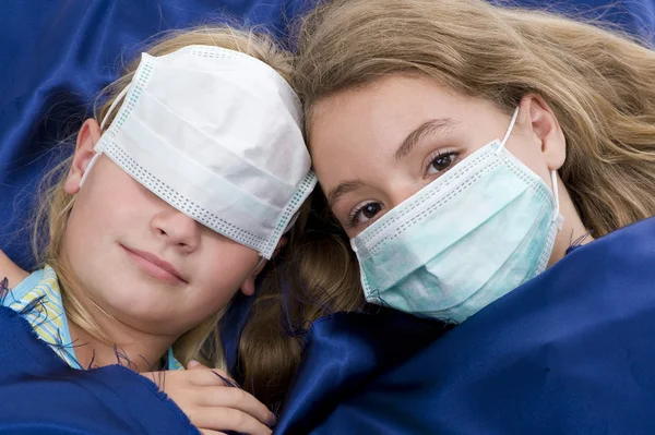Systrar i sängen med skyddande mask — Stockfoto
