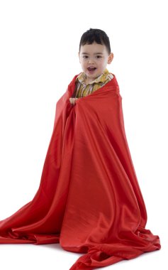 Beyaz arka plan üzerinde izole kırmızı ipek kumaş sarılmış mutlu çocuk
