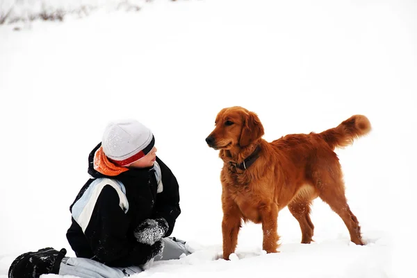 少女微笑的白种人男孩与室外在白雪皑皑的冬天背景的金毛狗 — 图库照片