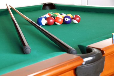 Billiards green table with balls and two black cues clipart