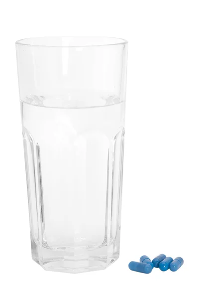 Szklankę wody i niebieskie tabletki — Zdjęcie stockowe