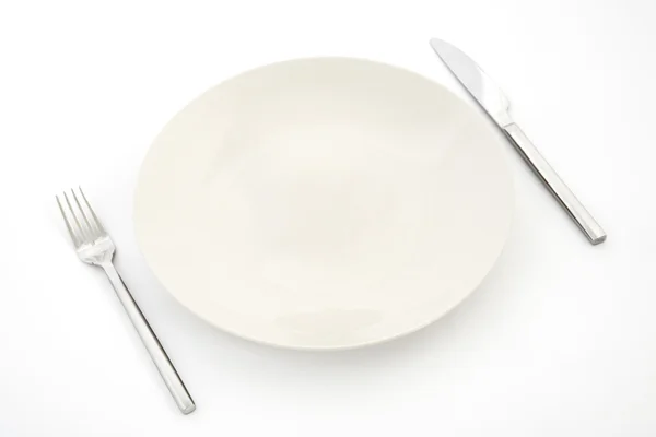 Нож, белая тарелка и вилка — стоковое фото