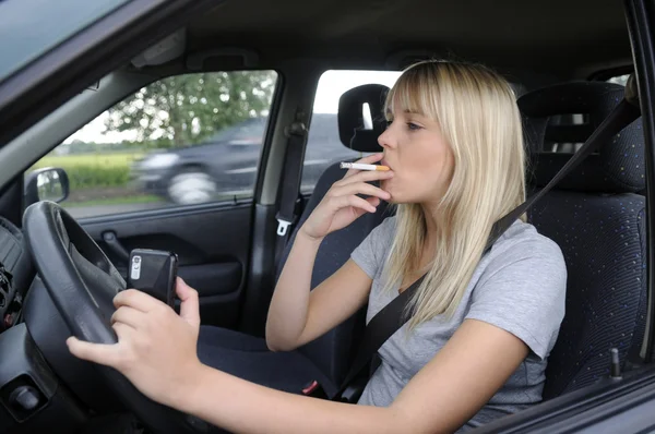Mujer con cigarrillo y teléfono móvil en el coche — Foto de Stock
