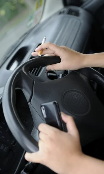 Mobile phone and cigarette at the wheel — Stock Photo, Image