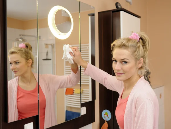 Huisvrouw reinigt een spiegel — Stockfoto