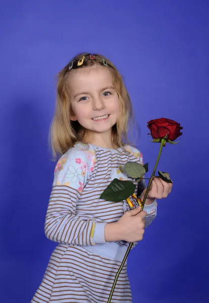 Blondes Kleines Mädchen Mit Roter Rose Vor Blauem Hintergrund — Stockfoto