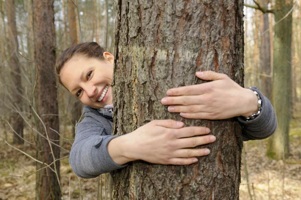Genç bir kadın ağaca sarılıyor. — Stok fotoğraf