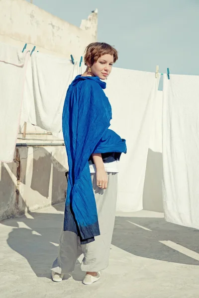 青のエスニックの布に美しい若い女性ハング屋根の上の乾燥タオル — ストック写真