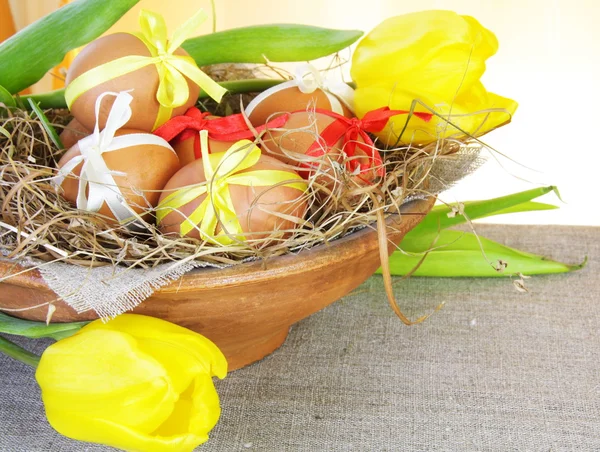 Bruin Pasen eieren in nesten kom met tulpen — Stockfoto