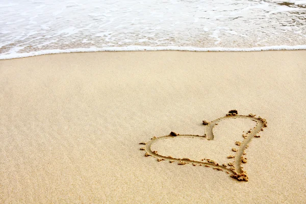 Corações desenhados na areia com seafoam e onda — Fotografia de Stock