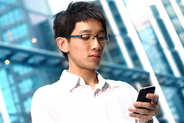 Casual asiático empresário mensagens de texto em seu telefone celular — Fotografia de Stock