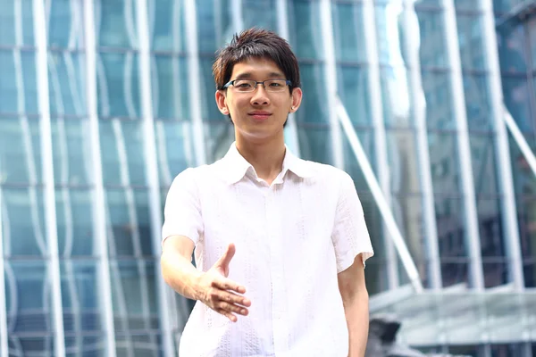 Aziatische zakenman aanbieden voor handdruk, kantoorgebouw als bac — Stockfoto
