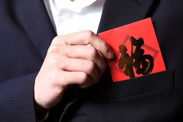 Businessman putting chinese cash gift in his pocket — Stock Photo, Image