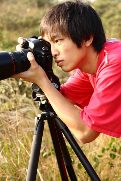 三脚にカメラとカメラマン 背景の黄色い草の上 — ストック写真