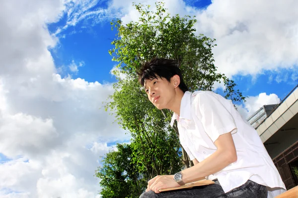 Genç Yakışıklı Bir Adam Oturuyor Mavi Gökyüzü — Stok fotoğraf