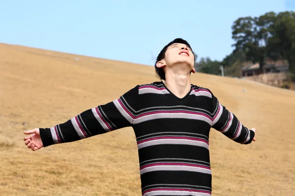 Unbekümmerter Mann steht auf goldenem Grasfeld und genießt glücklich — Stockfoto