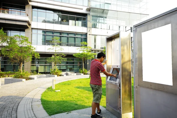 Asiatischer Junge spielt Touchscreen in modernem Gebäude draußen — Stockfoto