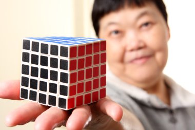 Senior chinese woman show a complete rubik cube clipart