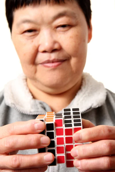 Senior chinese woman playing rubik cube — Stock Photo, Image