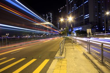 Blurred bus light trails in downtown night-scape clipart