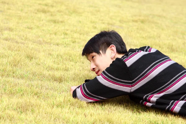 Ung man som ligger på gräs — Stockfoto