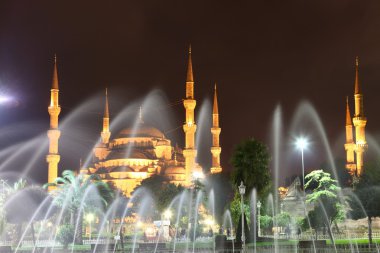 Illuminated Blue Mosque in Istanbul behind fountain at night clipart