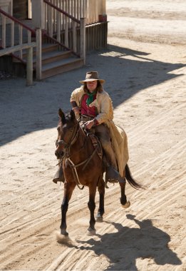 Cowboy riding his horse into town clipart