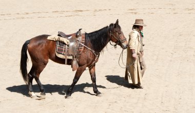 Cowboy walking his horse into town clipart