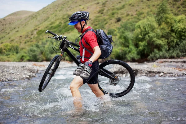 Motociclista passa pelo vau do rio da montanha — Fotografia de Stock