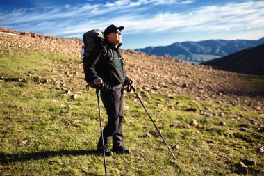 Backpacker admiring sunrise in mountains clipart