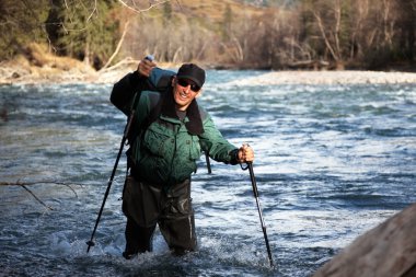 Backpacker wade rugged river clipart