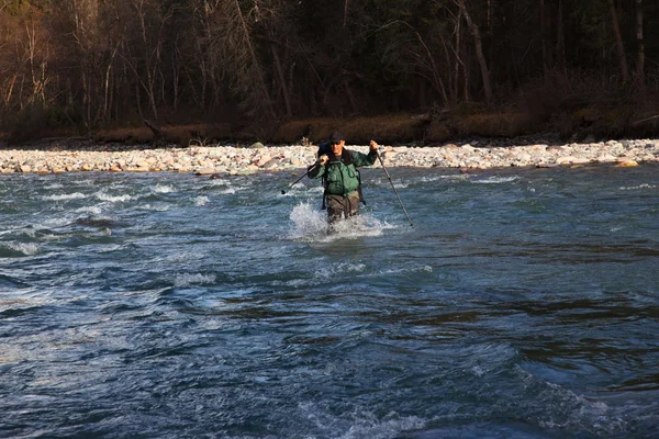 Backpacker waten durch rauen Fluss — Stockfoto