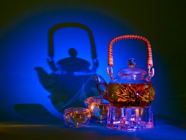 Green tea in a glass pot on a blue background clipart