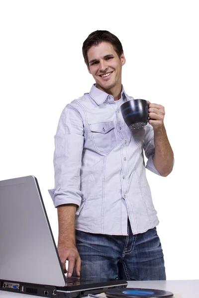 Молодой человек пьет кофе и работает на ноутбуке — стоковое фото