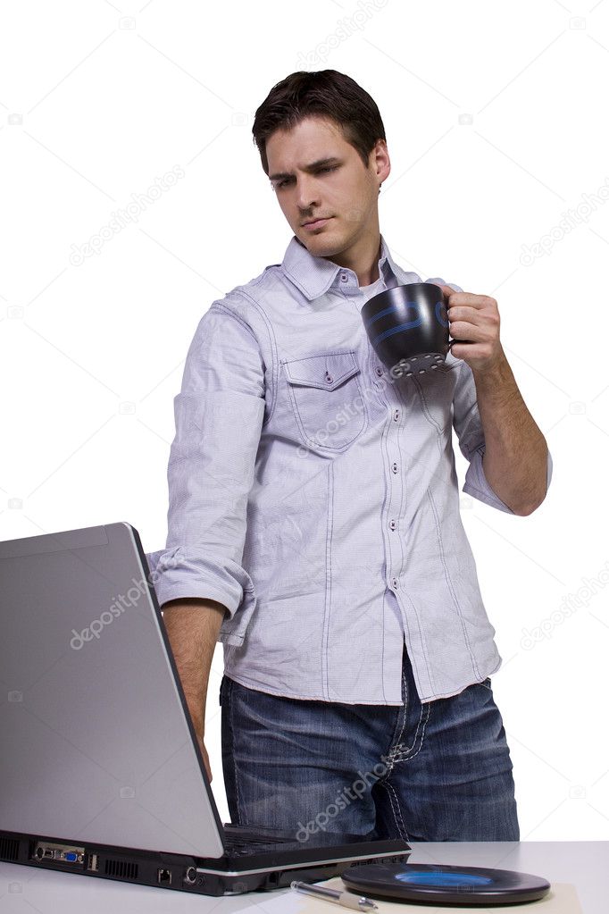 Young man drinking coffee and working on laptop