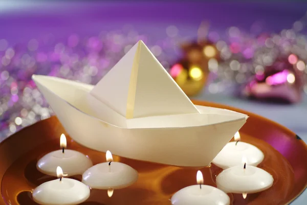 Плавучие свечи и бумажная лодка в миске с водой — стоковое фото