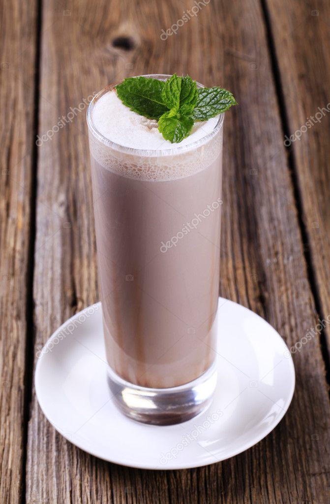 Glass of chocolate milk shake on wooden table