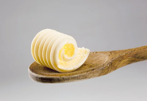 나무로 되는 숟가락에 버터 컬 — 스톡 사진