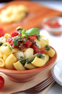 Macaroni with capers, crushed tomatoes and pesto clipart